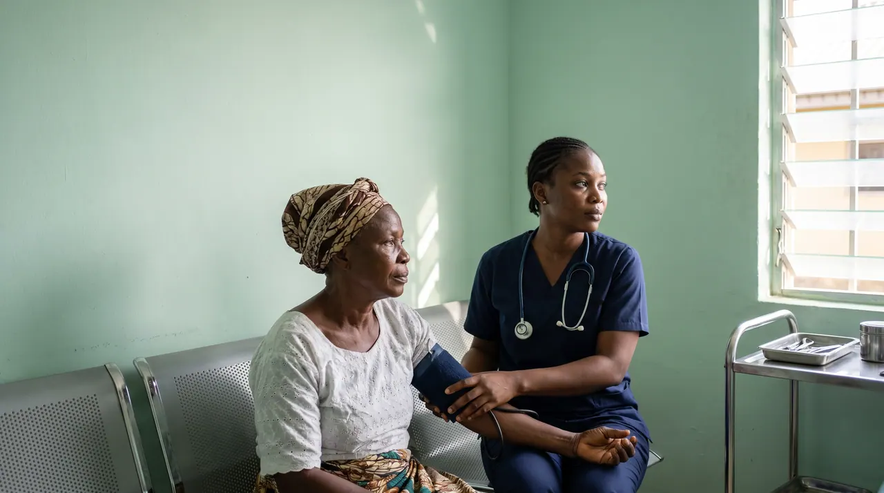 A nurse taking an older woman's blood pressure in a Nigerian community clinic
